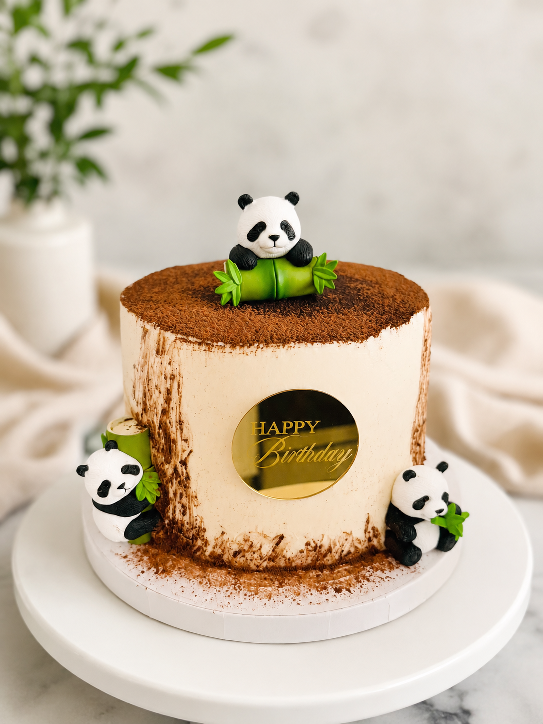 Woodland birthday cake decorated with three handcrafted panda figures